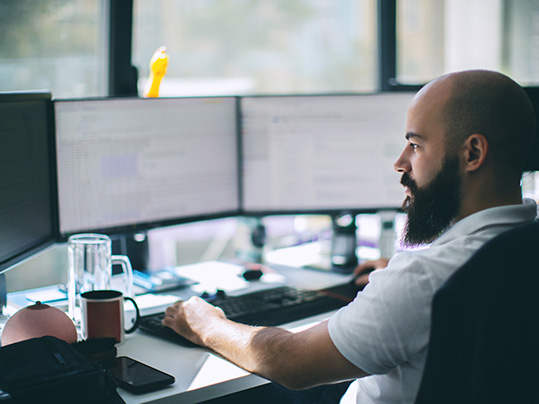 man working on multiple monitors