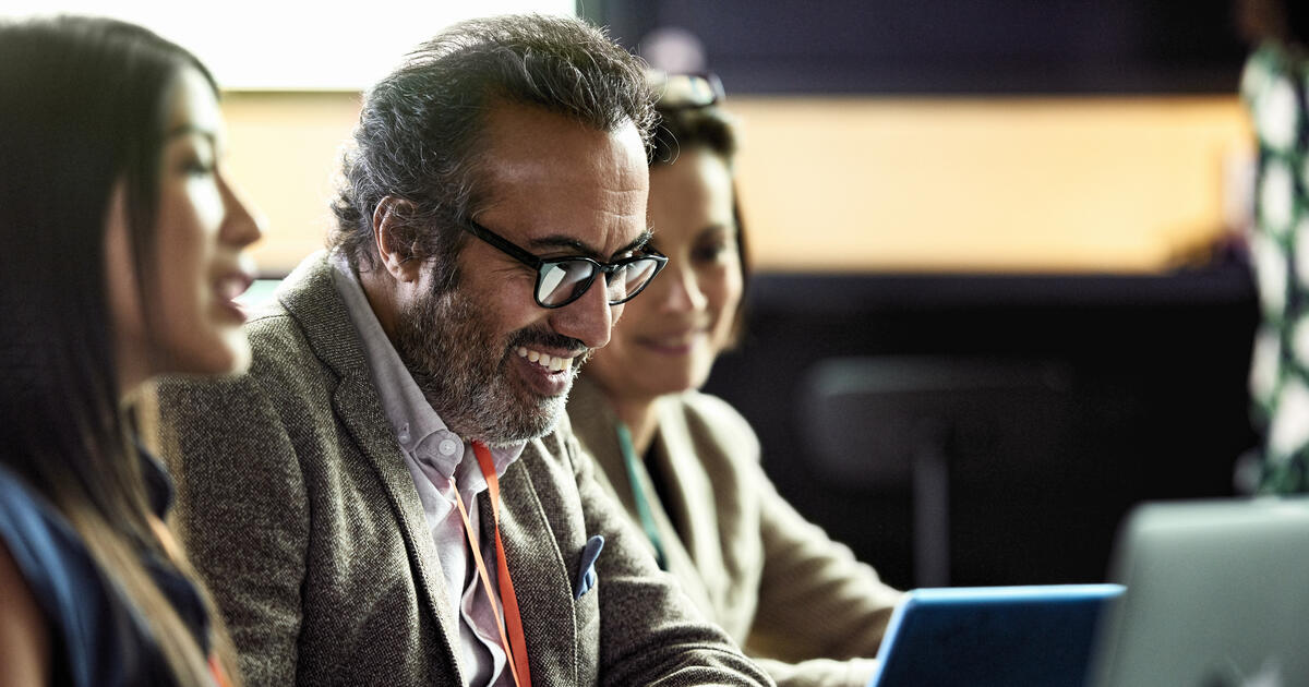 Smiling mature businessman looking at laptop at business meeting