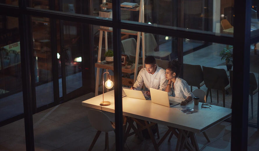 Shot of a young businessman and businesswoman using a laptop during a late night meeting at work