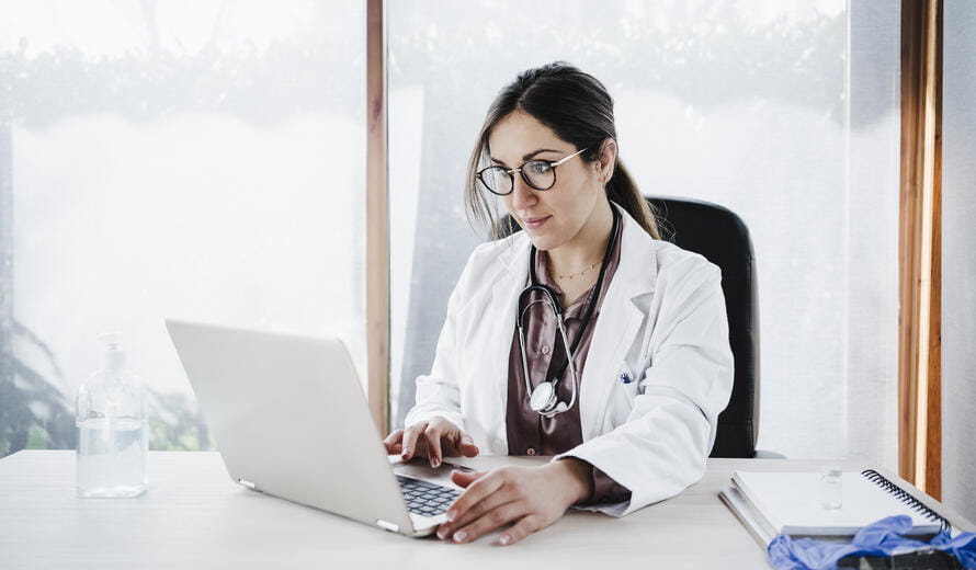 portrait of young doctor woman working in laptop in office, Madrid, Spain