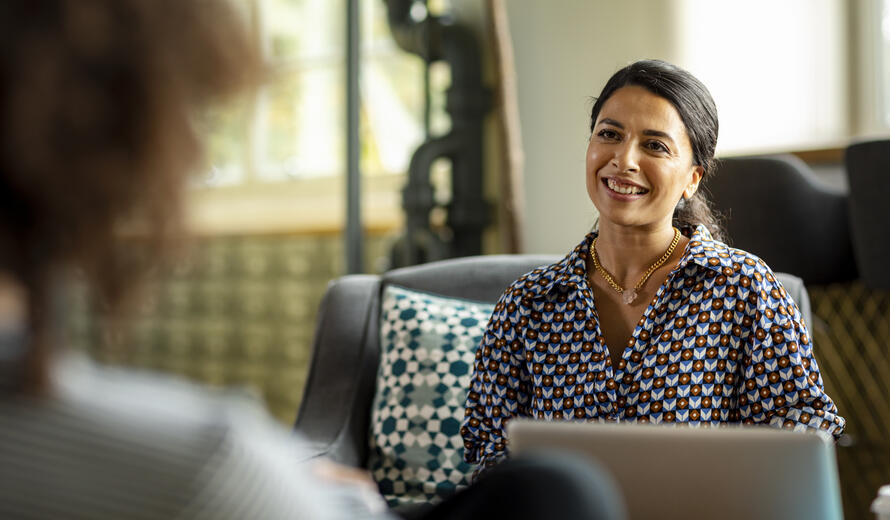 Confident woman in her 30s having informal meeting with business colleague in creative office discussing project, teamwork, togetherness, confidence