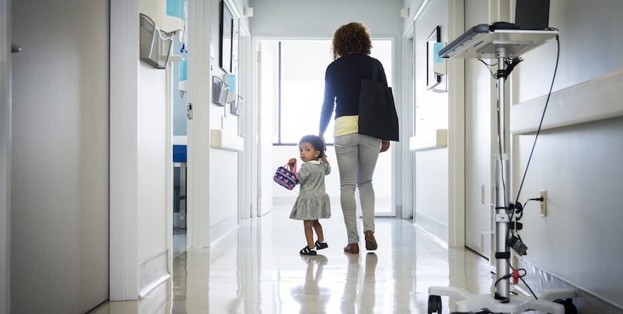 Mother and daughter walking through a rural health hospital